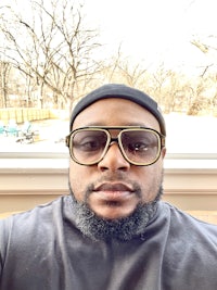 a black man wearing glasses and a hat